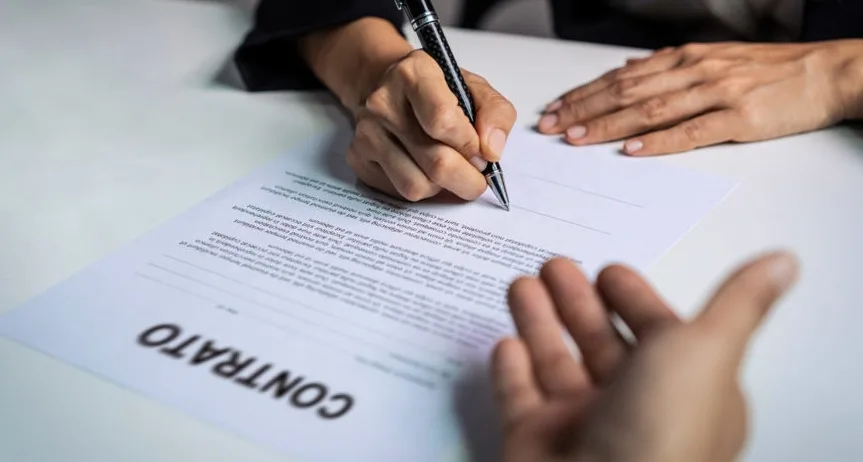 Pessoa assinando contrato de serviço contratado pela internet, atenta às cláusulas de cancelamento.